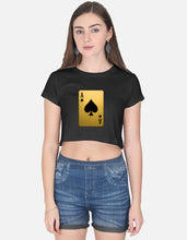 Woman wearing a black crop top with a gold playing card design and blue denim shorts on a white background