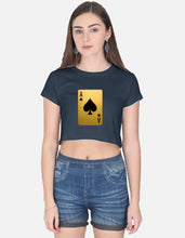 Woman wearing a navy blue crop top with a gold playing card design and denim shorts on a white background