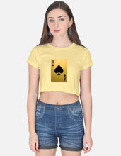 Woman wearing a yellow crop top with a playing card design and blue shorts on a white background