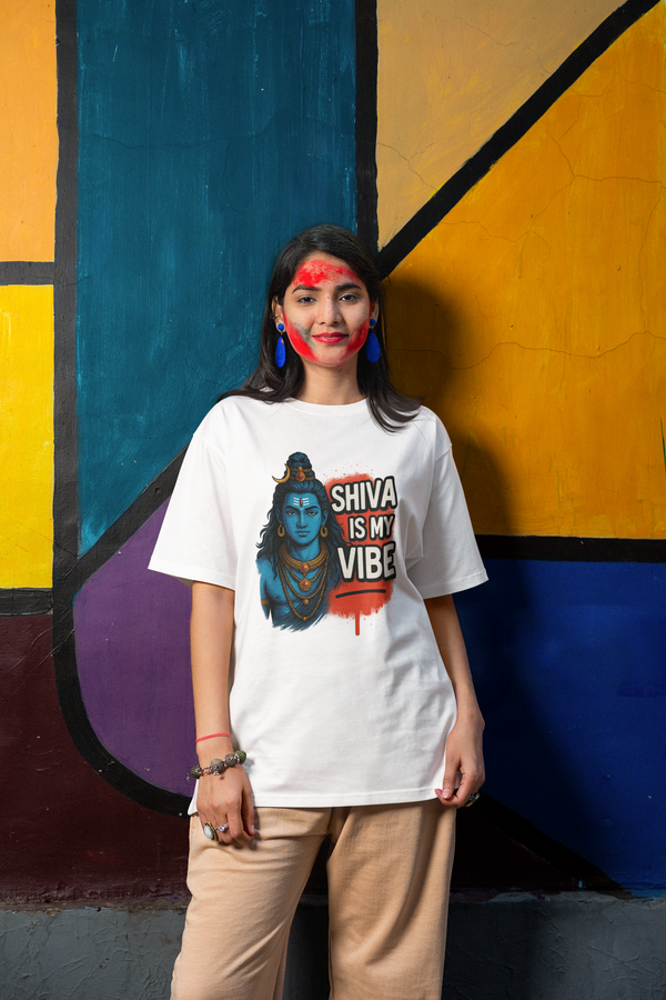 white t-shirt with 'Shiva is my vibe' design against a colorful abstract wall.