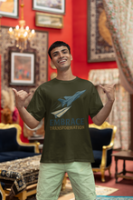 Man wearing a green t-shirt with 'Embrace Transformation' text and airplane graphic in a decorated room.