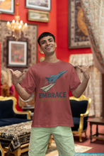 Man wearing a red t-shirt with a graphic design and text, standing in an ornate room.