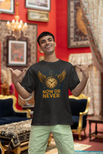 Man wearing a black t-shirt with 'Now or Never' design in a decorated room.