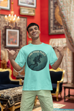 Man wearing a light blue t-shirt with a graphic design in a decorated room.