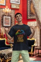 Man wearing a black t-shirt with 'Love Out Loud' design in a decorated room.