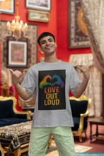 Man wearing a t-shirt with 'Love Out Loud' design in a decorated room.