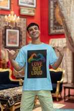 Man wearing a light blue t-shirt with a colorful design and text in a decorated room.