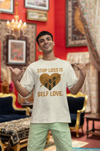 Man wearing a t-shirt with 'Stop Loss is Self Love' design in a decorated room.