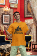 Man wearing a yellow t-shirt with a motorcycle graphic and text in a decorated room.