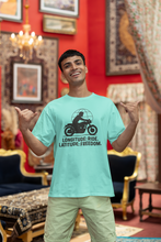 Man wearing a light blue t-shirt with a graphic design and text, standing in an ornate room.