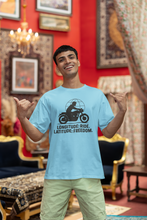 Man wearing a light blue t-shirt with a graphic and text, standing in an ornate room.