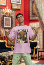 Man wearing a pink t-shirt with a dog adoption message in a decorated room.