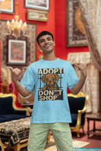 Man wearing a blue t-shirt with an 'Adopt Don't Shop' graphic in a decorated room.