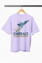 Lavender t-shirt with graphic design and 'Embrace Transformation' text on a hanger against a white background