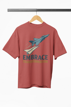 Red t-shirt with a graphic of a rocket and 'Embrace Transformation' text on a hanger against a white background