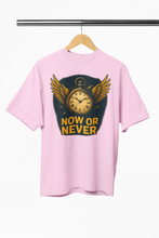 Man wearing a yellow t-shirt with 'Now or Never' design in a decorated room.