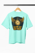 Mint green t-shirt with a clock and wings graphic and 'NOW OR NEVER' text on a hanger.