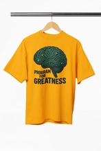 Yellow t-shirt with a brain graphic and 'Program for Greatness' text on a hanger.