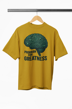 Yellow t-shirt with brain graphic and 'Program for Greatness' text on a hanger.