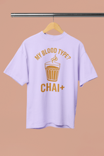 Light purple t-shirt with yellow text and graphic on a hanger against a beige background