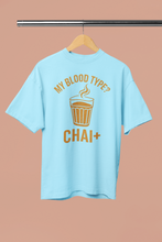 Light blue t-shirt with yellow text and graphics on a hanger against a beige background