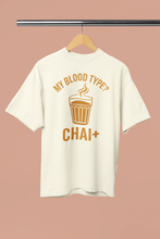 White t-shirt with 'My Blood Type? Chai+' design on a hanger against a pink background