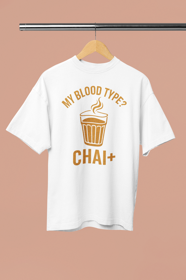 White t-shirt with 'My Blood Type? Chai+' design on a hanger against a beige background
