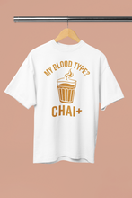 White t-shirt with 'My Blood Type? Chai+' design on a hanger against a beige background