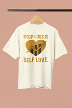 White t-shirt with gold graphic and text on a hanger against a beige background