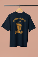 Black t-shirt with yellow text 'My blood type? CHAI+' on a beige background