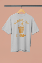 Gray t-shirt with 'My blood type? Chai+' text on a hanger against a beige background