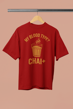 Red t-shirt with yellow text and graphic on a hanger against a beige background