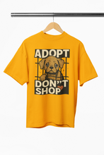 Yellow t-shirt with a dog graphic and 'Adopt Don't Shop' text on a hanger.