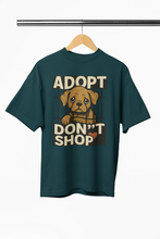 Green t-shirt with 'ADOPT DON'T SHOP' text and dog graphic on a hanger.