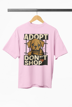 Pink t-shirt with 'Adopt Don't Shop' graphic on a hanger against a white background