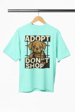 Mint green t-shirt with a dog graphic and 'Adopt Don't Shop' text on a hanger.