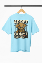 Light blue t-shirt with a dog graphic and 'Adopt Don't Shop' text on a hanger.