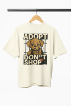 White t-shirt with 'Adopt Don't Shop' graphic featuring a dog on a hanger against a white background.