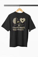 Black t-shirt with brain and heart graphic and 'Strong Minds. Kind Hearts.' text on a hanger.