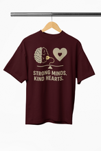 Maroon t-shirt with brain and heart design on a hanger against a white background