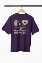 Purple t-shirt with 'Strong Minds. Kind Hearts.' text and graphics on a hanger.