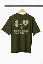 Green t-shirt with brain and heart design and 'Strong Minds. Kind Hearts.' text on a hanger.