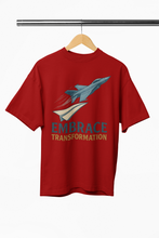 Red t-shirt with airplane graphic and 'Embrace Transformation' text on a hanger.