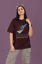 Person wearing a maroon t-shirt with a graphic and text on a purple background