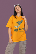 Person wearing a yellow t-shirt with a rocket graphic and 'Embrace Transformation' text on a purple background