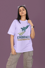 Person wearing a light purple t-shirt with a graphic and text 'Embrace Transformation' on a purple background