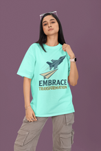 Person wearing a teal t-shirt with a graphic and text on a purple background
