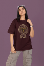 Person wearing a maroon t-shirt with a graphic design and text on a purple background