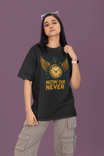 Person wearing a black t-shirt with a clock design and 'Now or Never' text on a purple background