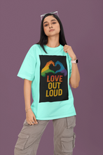Person wearing a teal t-shirt with a rainbow heart design and 'Love Out Loud' text on a purple background